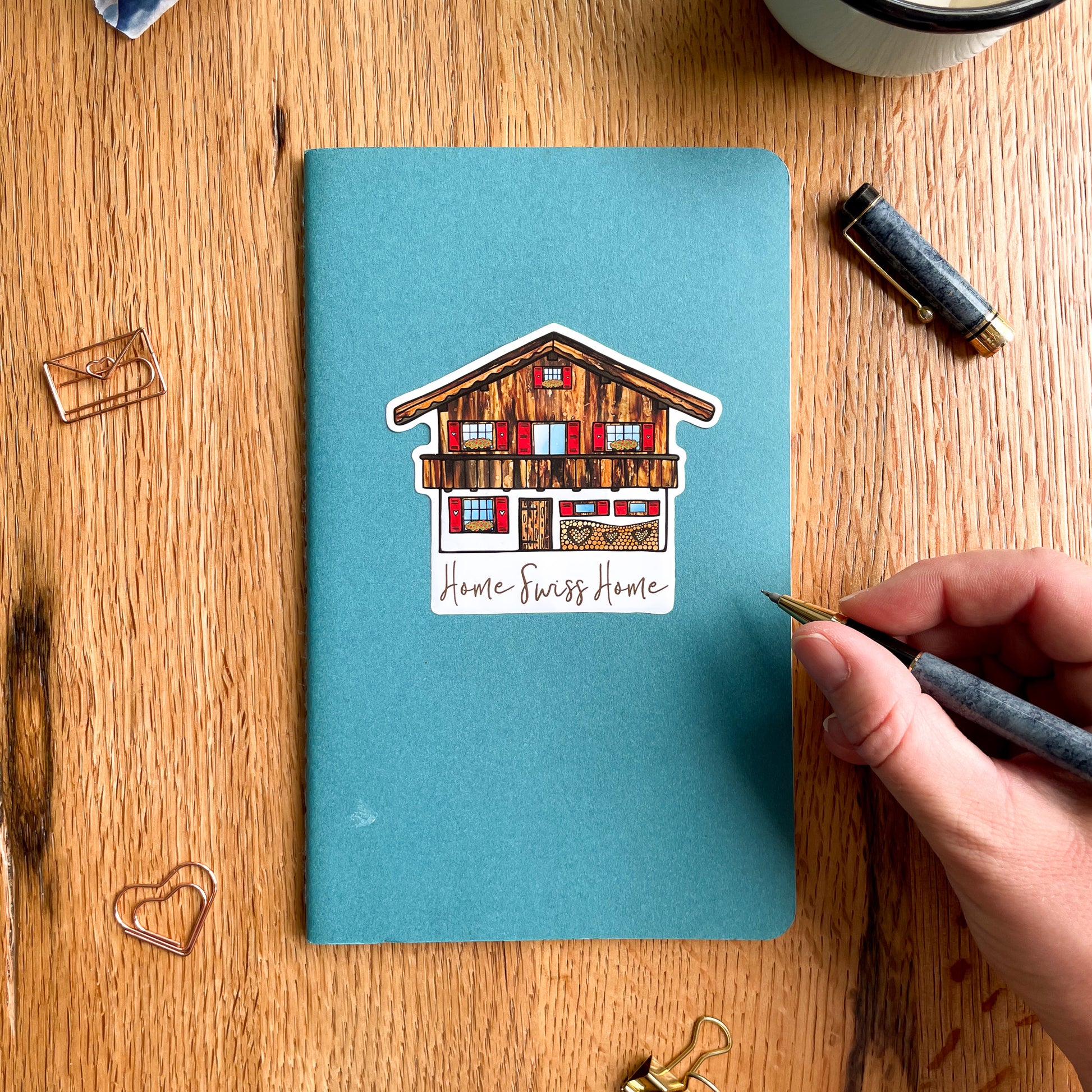 A charming Swiss Chalet vinyl sticker, perfect for adding a touch of idyllic Swiss house vibes to your travel journal.